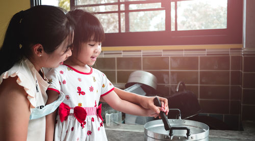 Mother and girl holding camera at home