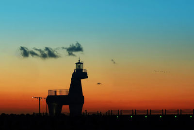 Low angle view of silhouette lighthouse against sky during sunset