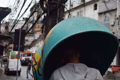 Rear view of man carrying container in city