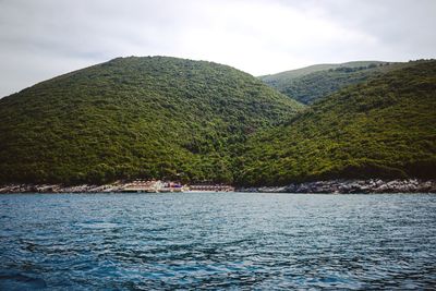 Scenic view of sea by mountains against sky
