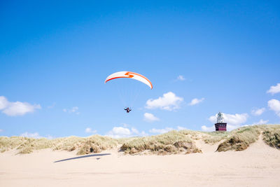 Low angle view of person paragliding against clear blue sky