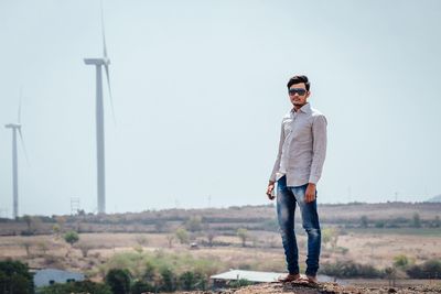 Full length portrait of young man standing against sky