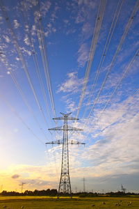 Low angle view of electricity pylon against sky during sunset