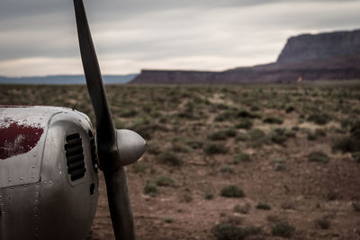 Close-up of airplane on landscape against sky