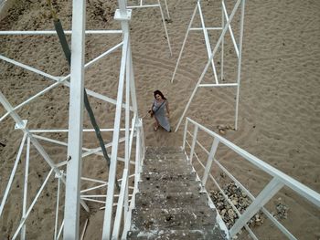 High angle view of woman standing by lookout tower steps at sandy beach