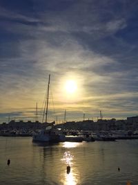 Sailboats in sea at sunset