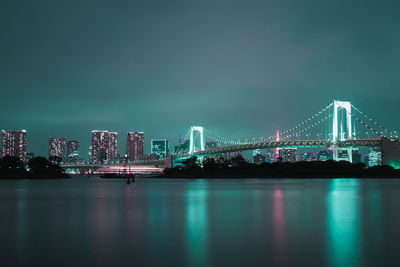 Illuminated city at waterfront during night