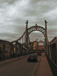 Suspension bridge against cloudy sky