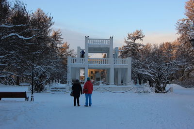 People walking on snow covered trees against sky