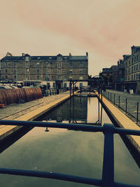 Bridge over river amidst buildings in city against sky