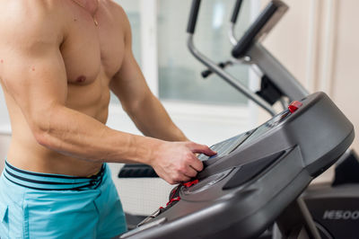 Shirtless young man on treadmill in gym