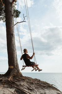 Swings on a cliff, man lookinga t sea horizon