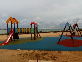 Playground on beach against sky