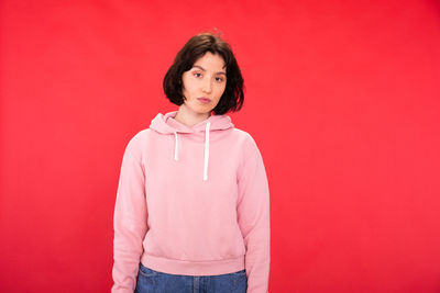 Portrait of woman standing against red wall