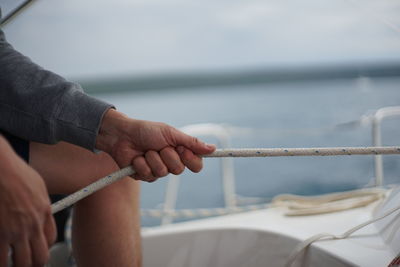 Midsection of man holding rope on boat