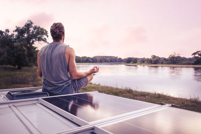 Rear view of man standing by lake against sky