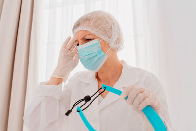 Female doctor wearing mask with face shield looking away