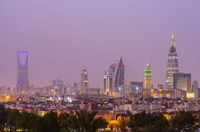 Illuminated buildings in city against clear sky