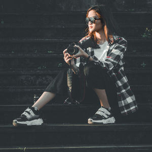 Full length of woman photographer with her slr camera is sitting on the staircase