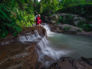 Man surfing on rock against waterfall