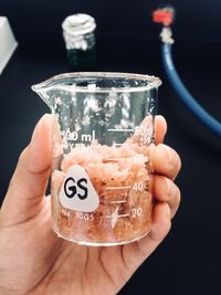 Cropped hand holding chemical in container at laboratory