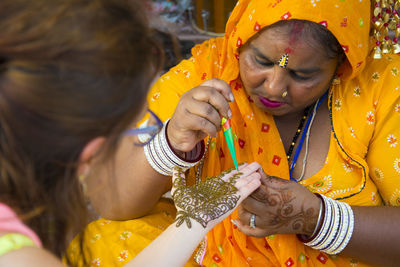 Woman applying henna tattoo on customer hand