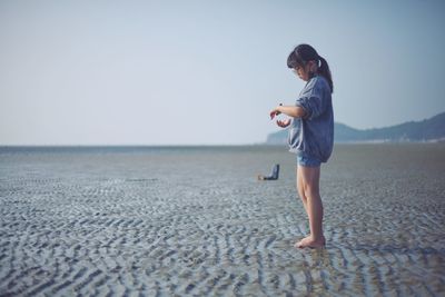 Full length of man standing on beach against clear sky