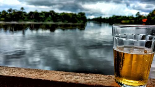 Close-up of beer glass against water