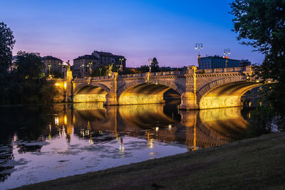 Bridge over river against sky at sunset