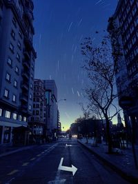 Road by buildings against sky in city at night