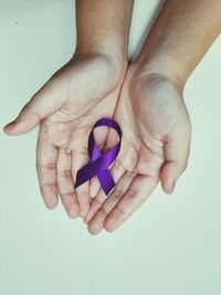 Close-up of hand holding purple against blue background