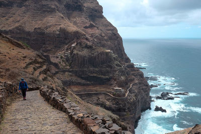 Full length of woman hiking on walkway by sea