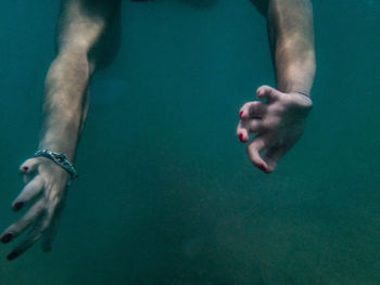 Cropped hand of woman swimming underwater in sea