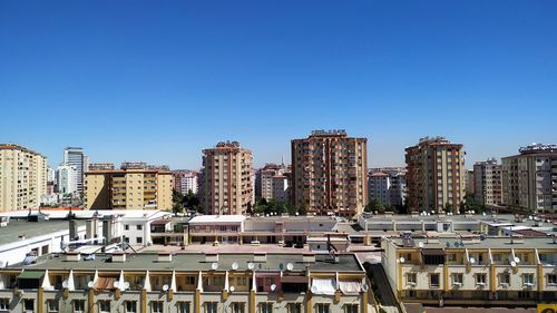 Buildings in city against clear blue sky