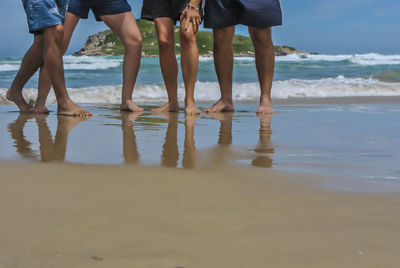 Low section of friends standing at beach