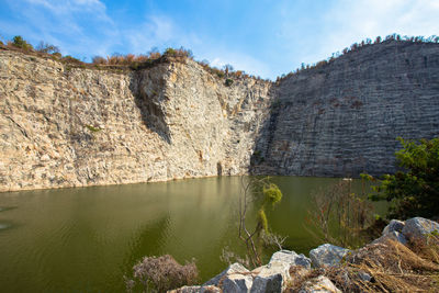 Rocks by lake against sky