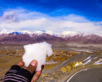 Midsection of person holding snowcapped mountain against sky