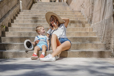 Full length of mother and son sitting on steps outdoors