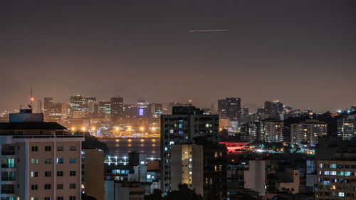 Illuminated buildings in city against sky at night