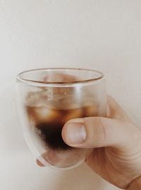 Close-up of hand holding drink against white background