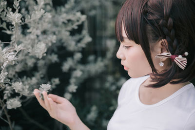 Close-up of woman looking at plant in park