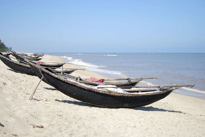 Boats moored at sandy beach on sunny day