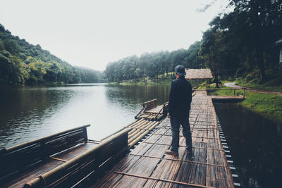 Rear view of man looking at lake against clear sky