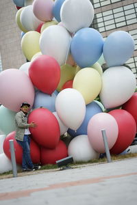 Full length of boy holding multi colored balloons