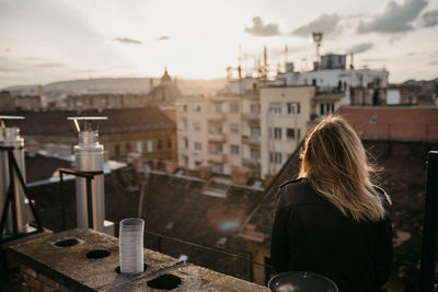 Rear view of woman standing in city against sky