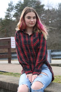 Portrait of young woman sitting on wall