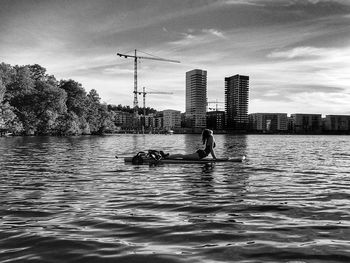Man in river against sky in city