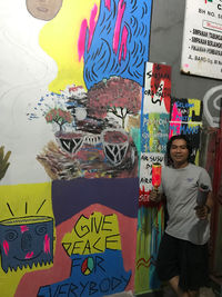 Full length of woman standing against graffiti wall