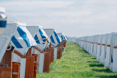 Hooded chairs on beach against sky