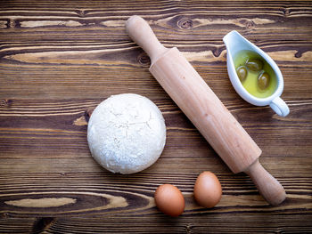 High angle view of eggs with dough and olives on wooden table